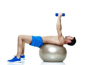 Physio Studio man on swiss ball with dumbbells