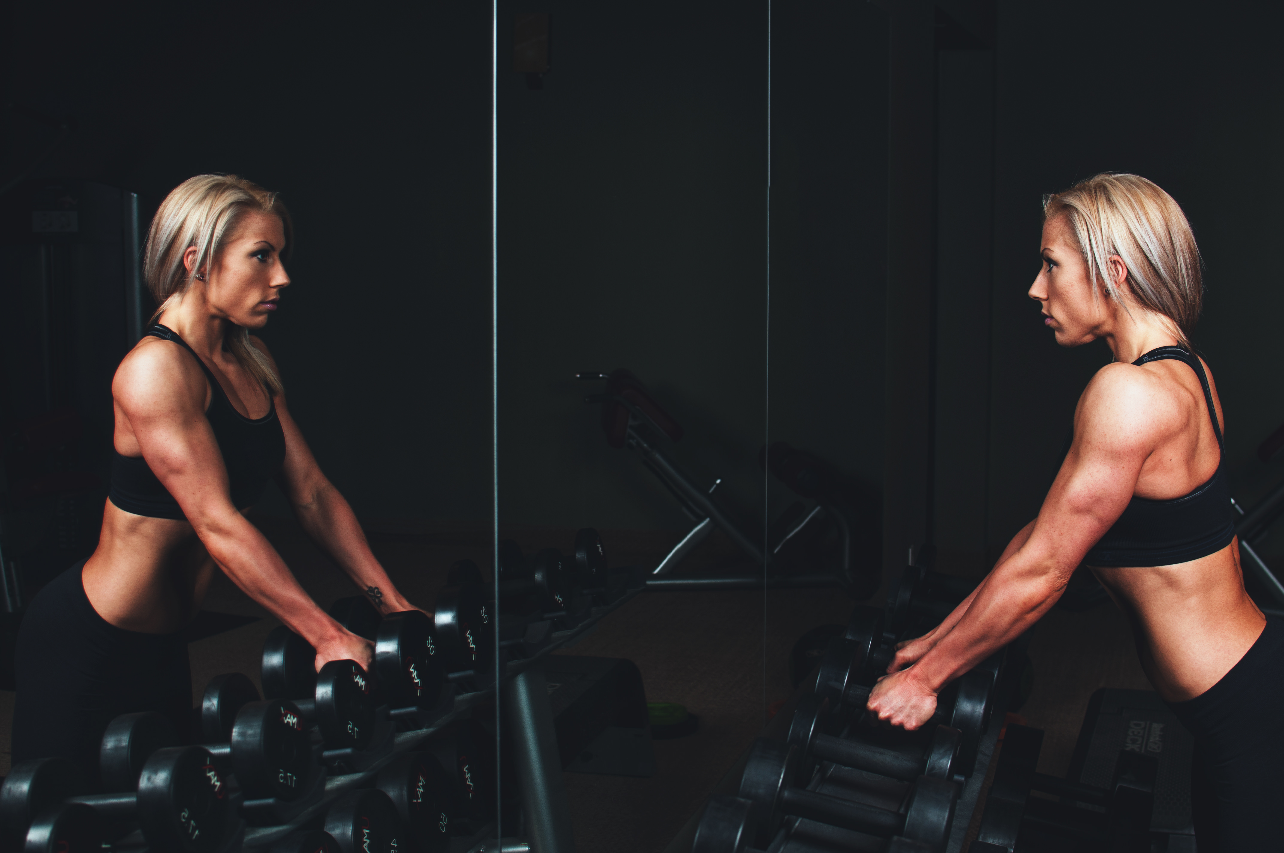 woman with dumbbells looking in mirror